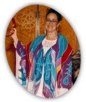 Rabbi Rayzel Raphael in colorful silk tallit and holding a tambourine